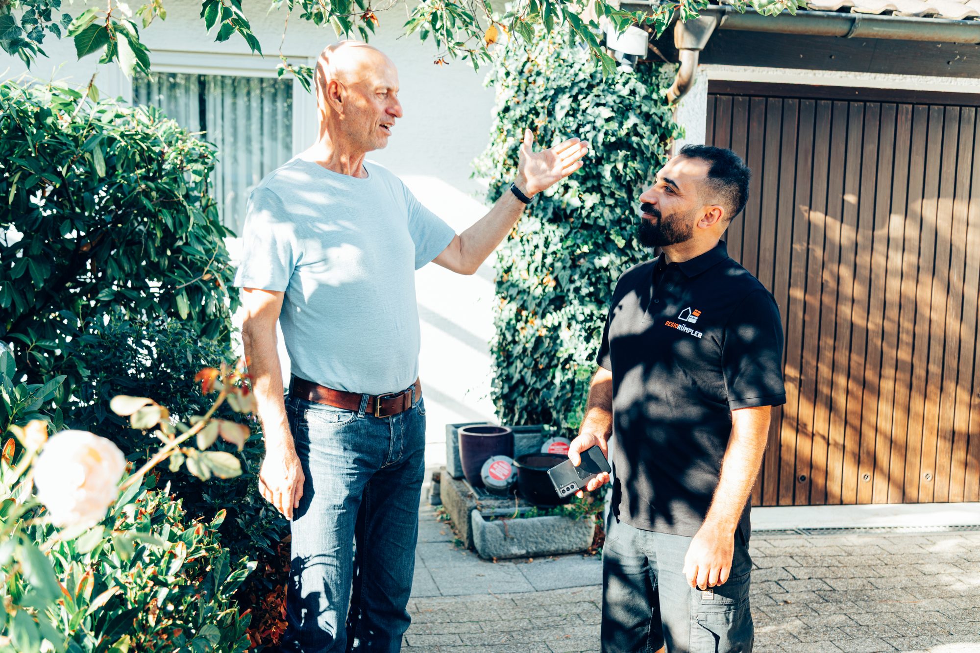Der Inhaber von RegioRümpler bespricht bei der Besichtigung im Garten mit einem Kunden die Räumung.
