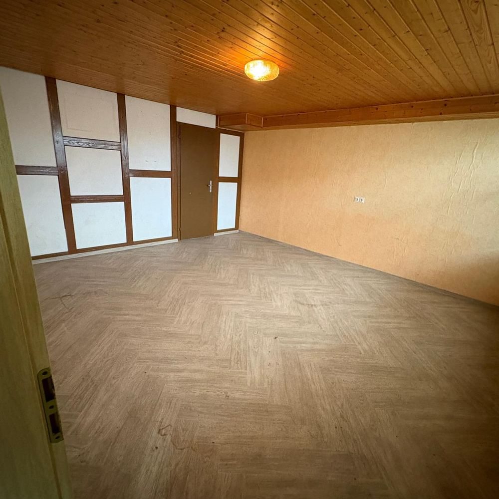 Dasselbe Wohnzimmer mit Holzdecke nach der Haushaltsauflösung, leergeräumt und gekehrt.