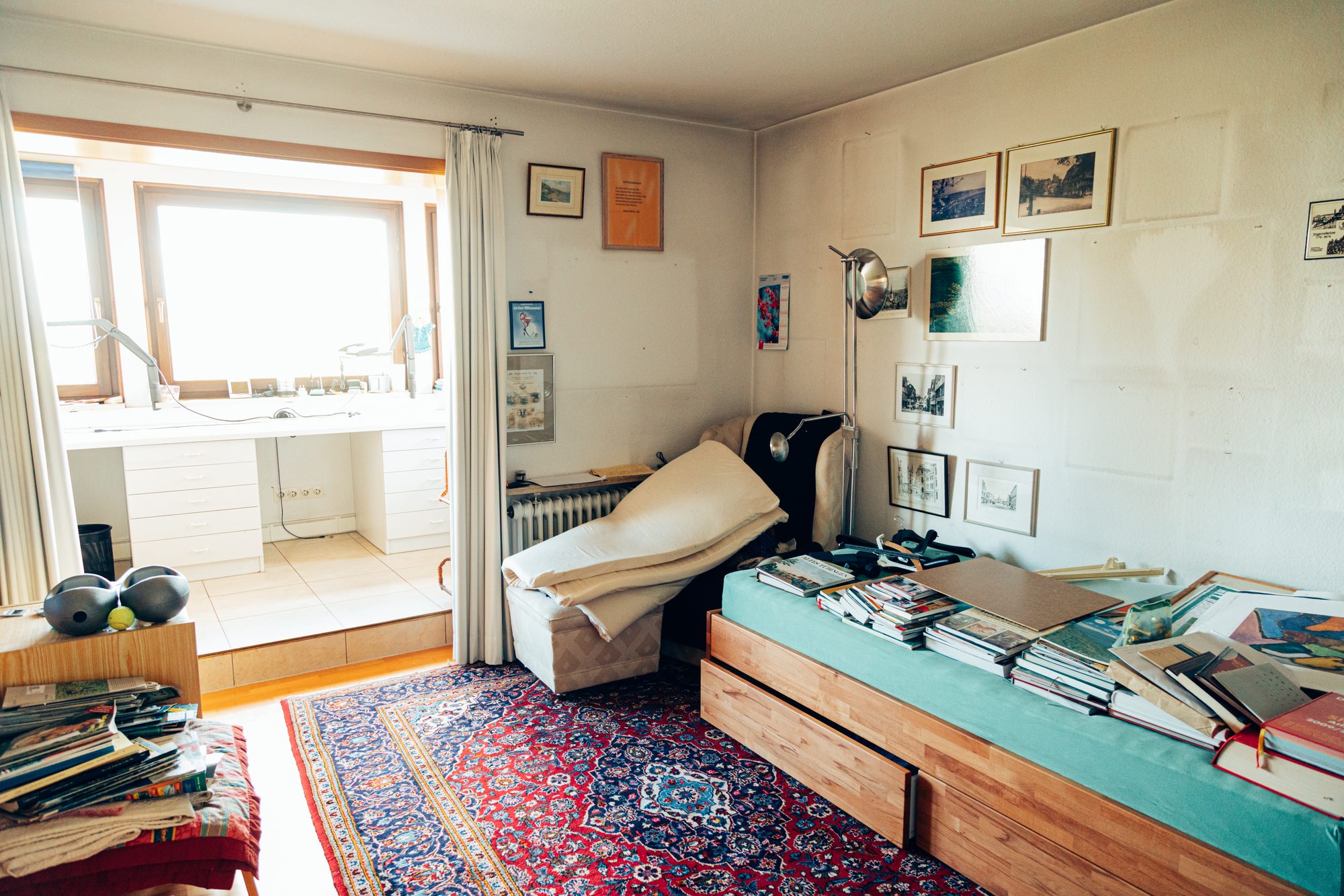 Arbeitszimmer mit Bücherstapeln auf dem Schlafsofa vor der Wohnungsentrümpelung.