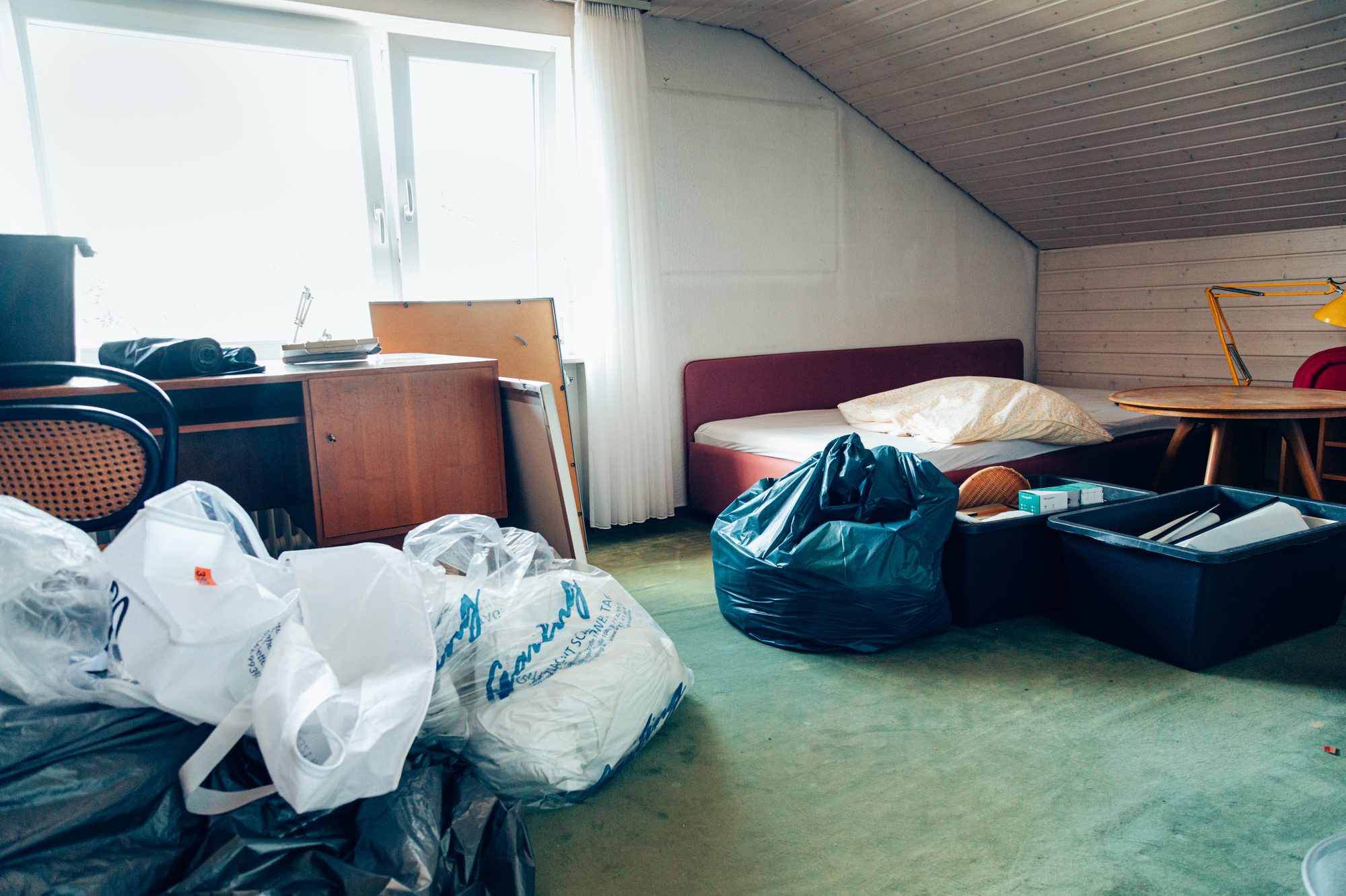 Dachzimmer voller Müllsäcke und alter Möbel vor der Wohnungsentrümpelung.