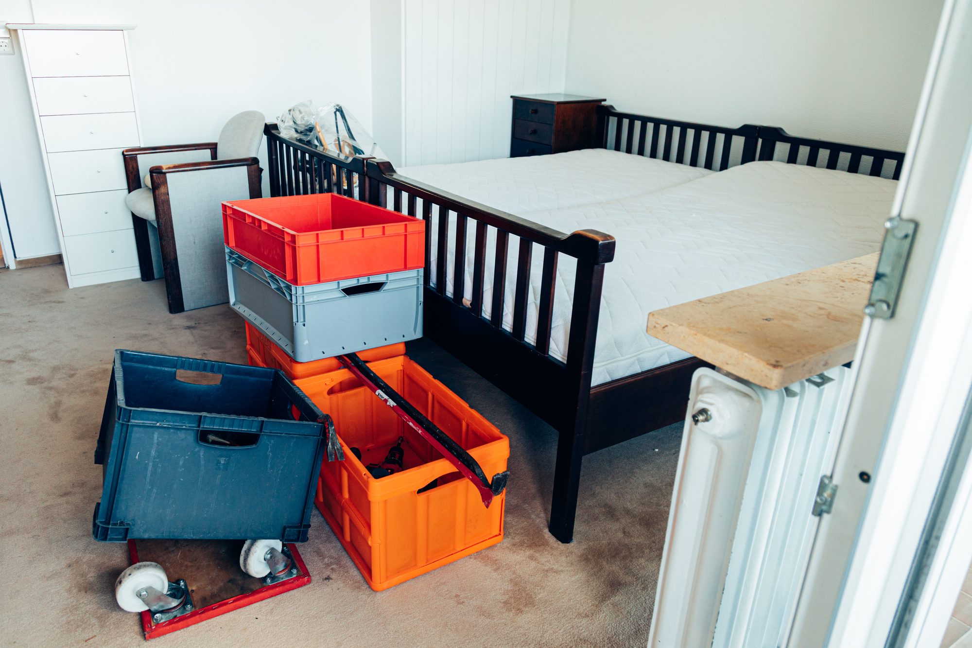 Schlafzimmer mit Doppelbett und bereitgestellten Transportkisten vor der Wohnungsentrümpelung.