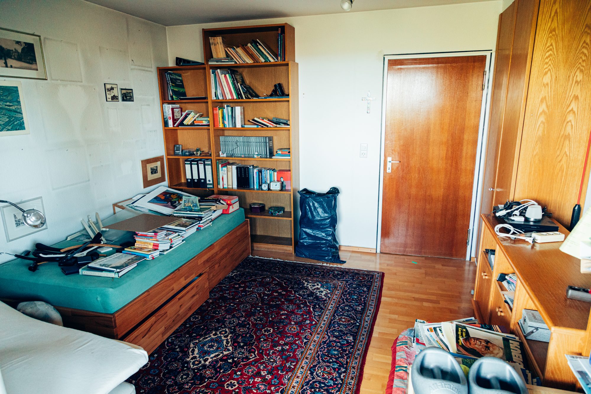 Zimmer mit vollem Bücherregal und Schlafsofa vor der Wohnungsentrümpelung.