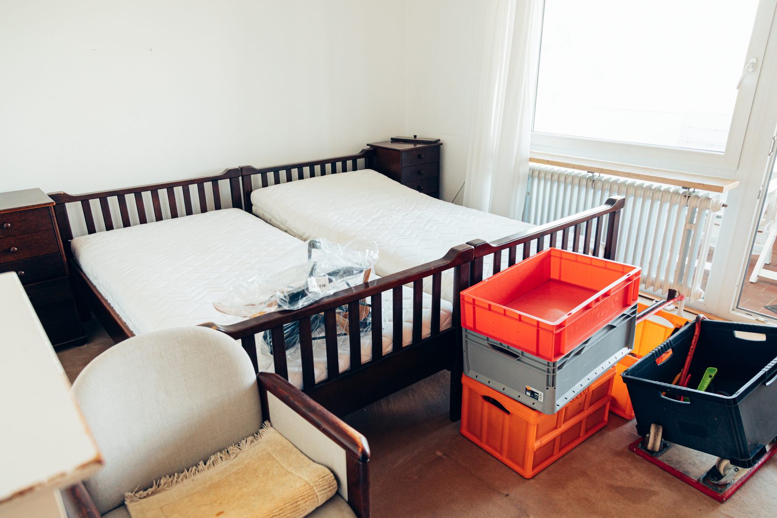 Schlafzimmer vor der Räumung mit Doppelbett, Sessel und bereitgestellten Transportkisten.